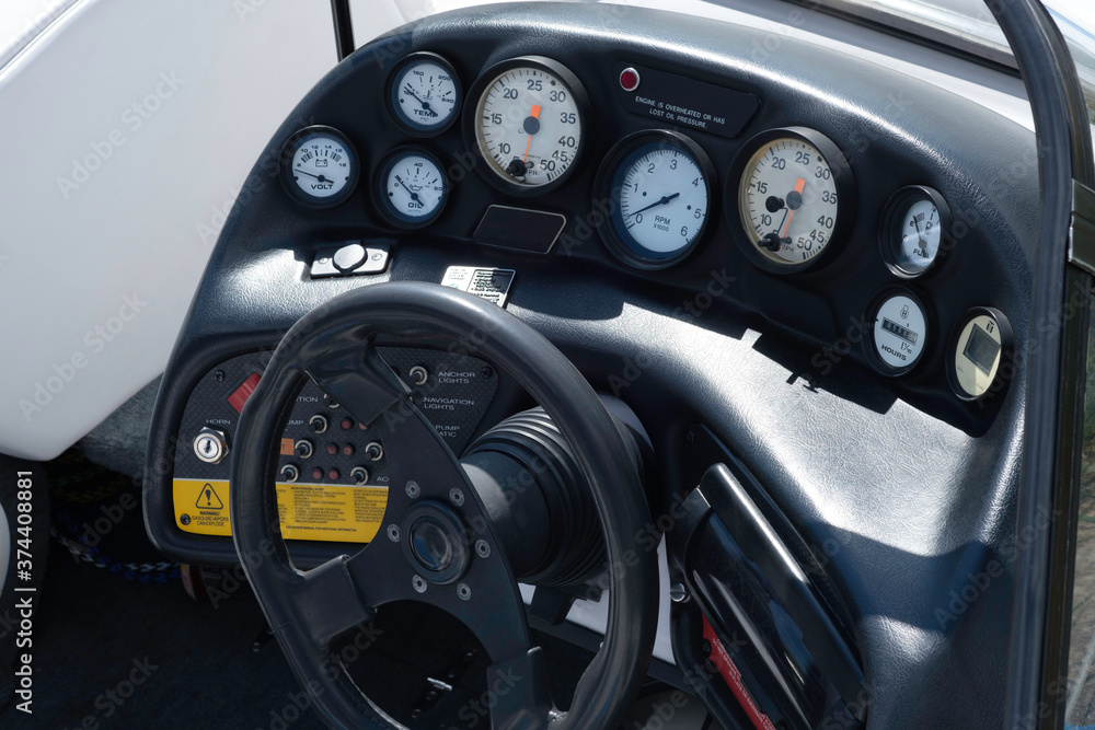 The cockpit of a speedboat showing all the gauges and steering wheel