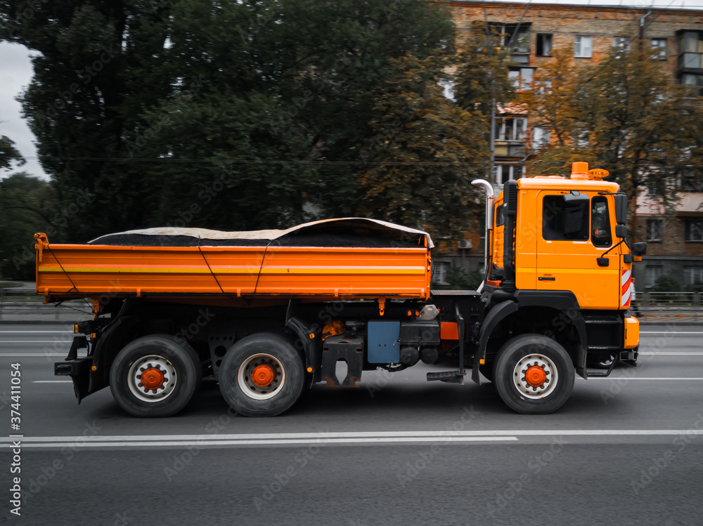 Orange city utility truck in motion on the road.