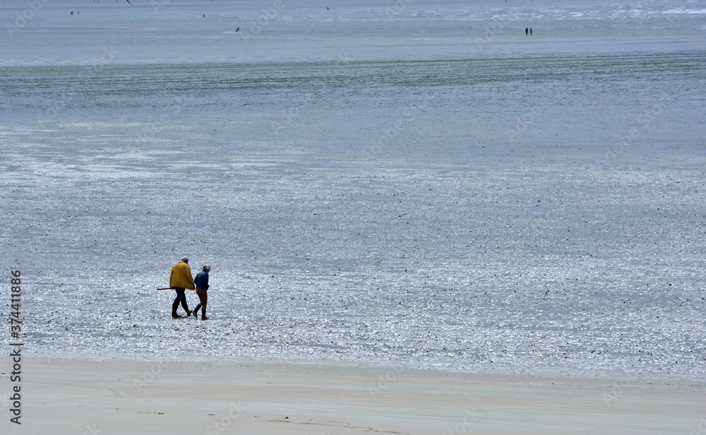 Couple of people walking on a beach in Brittany. France Couple of people walking on a beach in Brittany. France