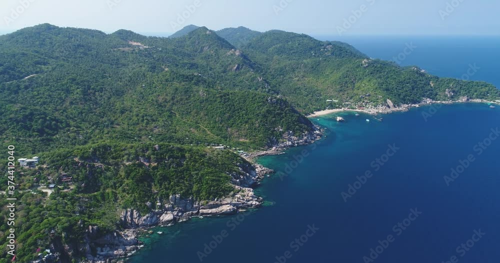 Thailand's highland island landscape aerial view: green jungle with coconut palm trees, sand beach on coast at blue calm water of ocean bay. Bird's eye Thai picturesque paradise. Pan shot in 4K, UHD Thailand's highland island landscape aerial view: green jungle with coconut palm trees, sand beach on coast at blue calm water of ocean bay. Bird's eye Thai picturesque paradise. Pan shot in 4K, UHD