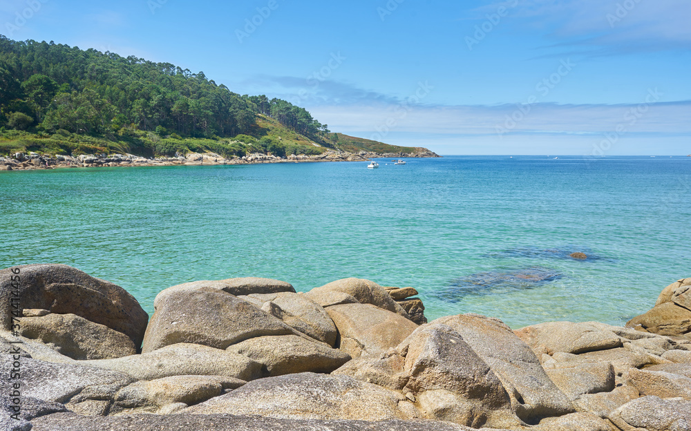 Beautiful photo of a sea with rocky stones and boats in the background