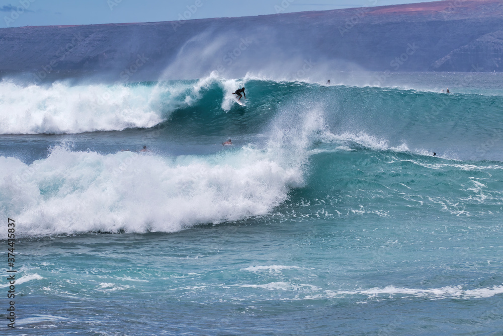 Obraz premium Unrecognizable surfer riding an enrgetic wave on Maui.