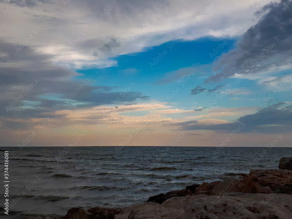 Sunset at the coast with cloudy sky in Italy. Evening sky with clouds at the beach.