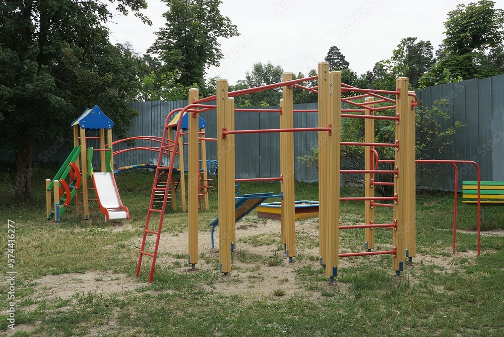 playground with horizontal bars, ladders and exercise equipment on the street in green grass against the background of a playground