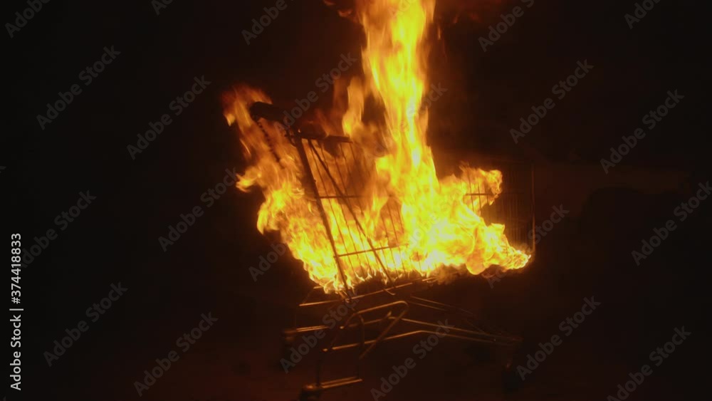 The shopping cart is on fire, in dump of car, dark night, slow mo The shopping cart is on fire, in dump of car, dark night, slow mo