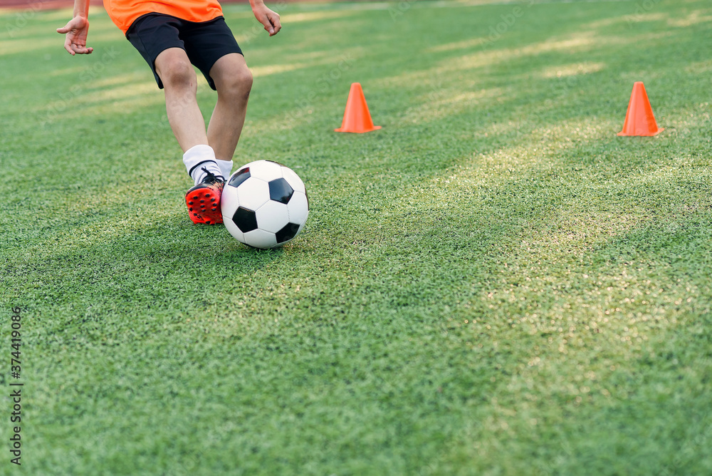 Soccer player kicking ball on field. Soccer players on training session. Close up footballer feet kicking ball on grass.