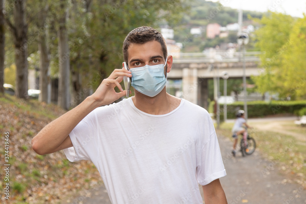 young man walking with mask and mobile phone young man walking with mask and mobile phone