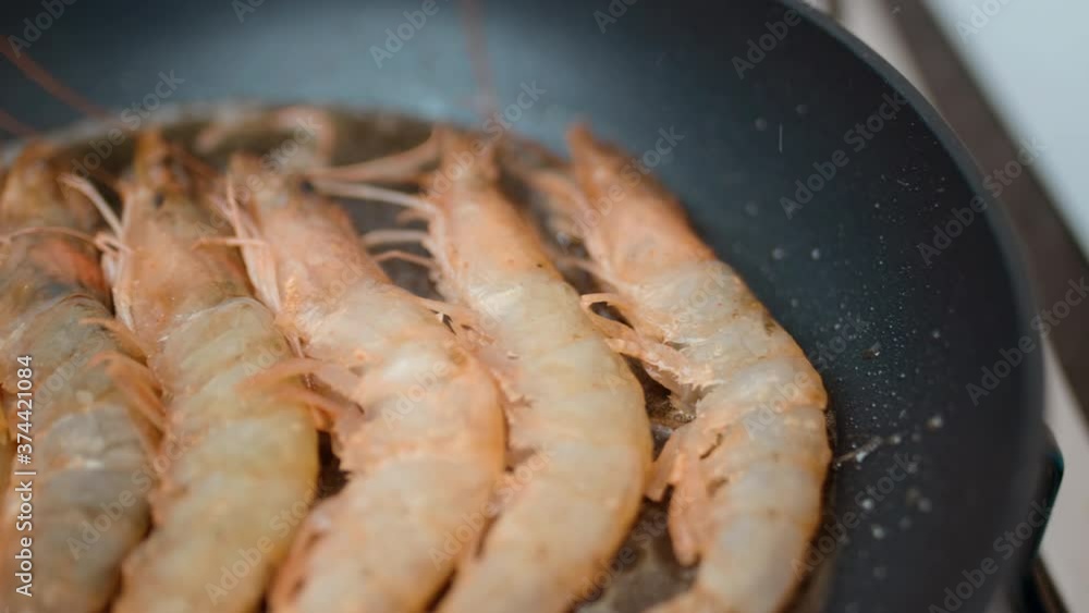 Adding/placing multiple prawns/shrimps in a frying pan with butter and oil in 4K. Concept of frying raw shrimps in slow motion. Adding/placing multiple prawns/shrimps in a frying pan with butter and oil in 4K. Concept of frying raw shrimps in slow motion.