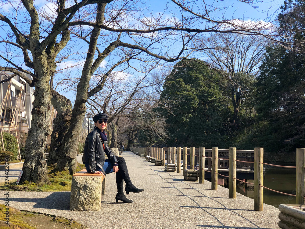 Woman sitting and seeing view around Kenrokuen garden and Kanazawa castle on her relax time.