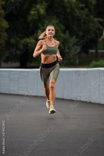 Caucasian Female Runner In Professional Outfit During Her Regular Training Exercises Outdoor.