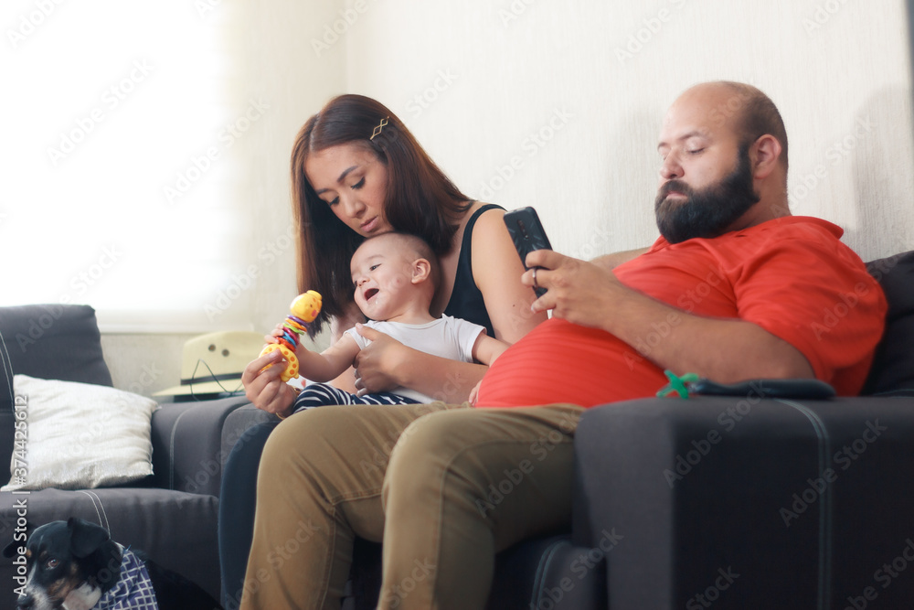 familia joven mexicana en sofa conviviendo con bebe viendo television Stock  Photo