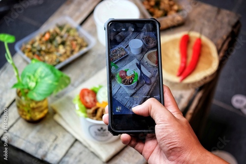 top view of people taking photo of food using phone, people snap photos of their food at home