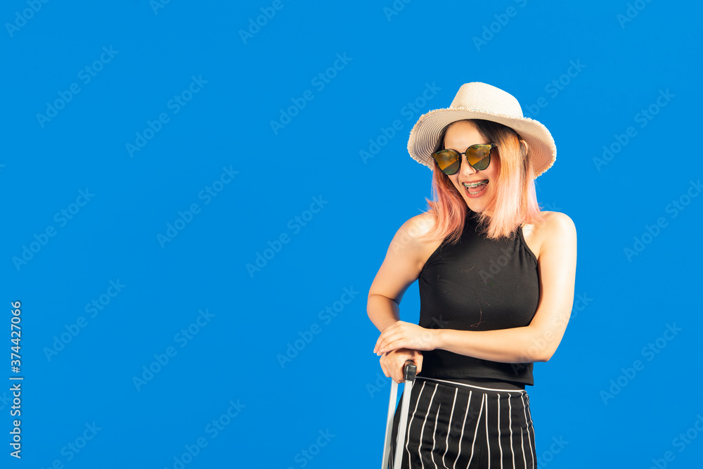 Fashion lifestyle portrait pretty asian woman in the sunglasses with suitcase posing in studio on blue background. Fashion lifestyle portrait pretty asian woman in the sunglasses with suitcase posing in studio on blue background.