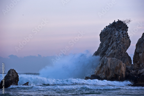 The seascape with huge wave and rocks.
