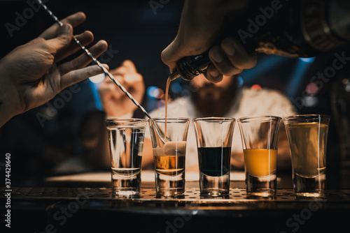 Bright cocktails - shots at the bar. Colorful footage in a nightclub. Alcoholic drink of different colors. Nightlife scene. Shots at the bar table. Several glasses of alcohol 