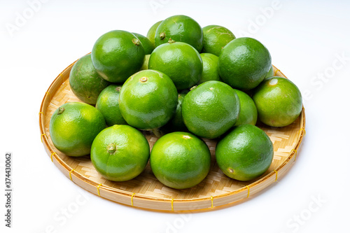 Fresh lime fruits in bamboo basket on white background