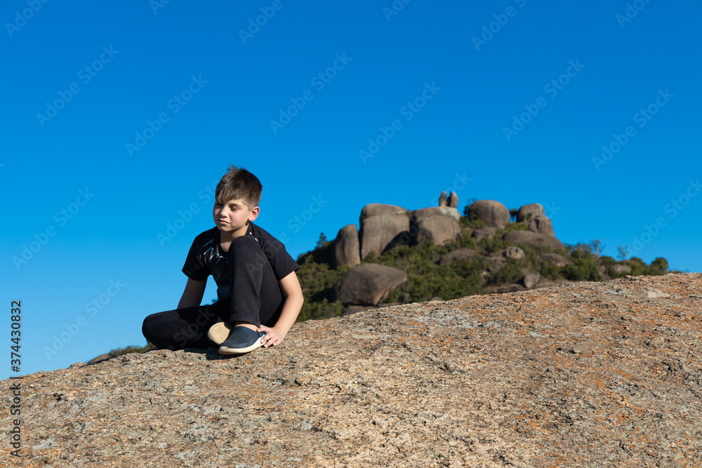 Menino no alto da Pedra Grande em Atibaia, admirando a paisagem. Cena de paz e tranquilidade. 