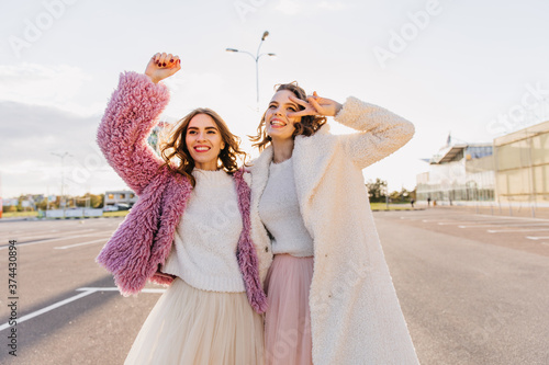 Short-haired lovely girl spending autumn day with her sister. Outdoor portrait of attractive ladies laughing on the street. © Look!