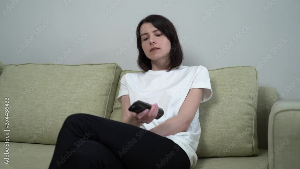 a woman with a remote control switches channels and laughs at the show a woman with a remote control switches channels and laughs at the show