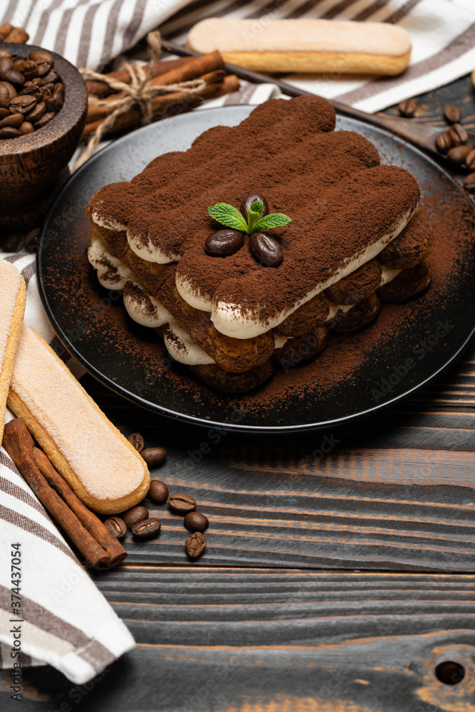Classic tiramisu dessert on ceramic plate and savoiardi cookies on wooden background Classic tiramisu dessert on ceramic plate and savoiardi cookies on wooden background
