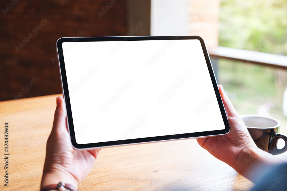 Mockup image of a woman holding digital tablet with blank white desktop screen in cafe Mockup image of a woman holding digital tablet with blank white desktop screen in cafe