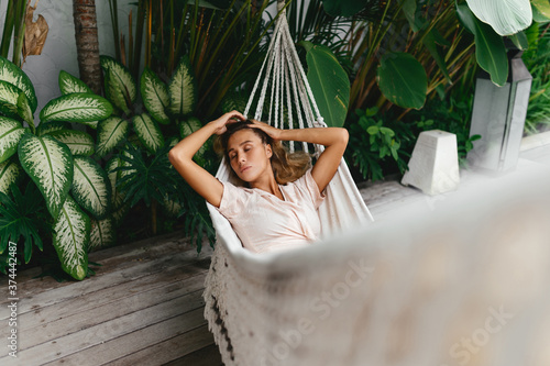 Young beautiful woman relaxing in hammock in a tropical resort
