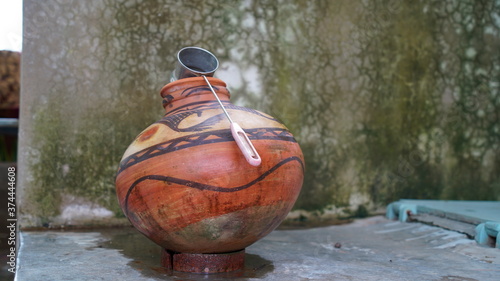 Red Clay pot with stainless steel glass in a house corner. Stylish printed art, ancient India culture to make pot.
