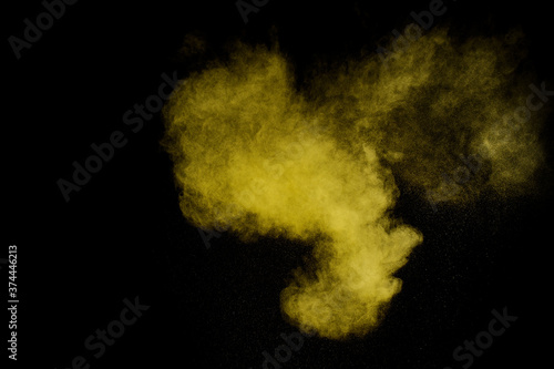 Yellow powder explosion on black background. Colored powder cloud. Colorful dust explode. Paint Holi.