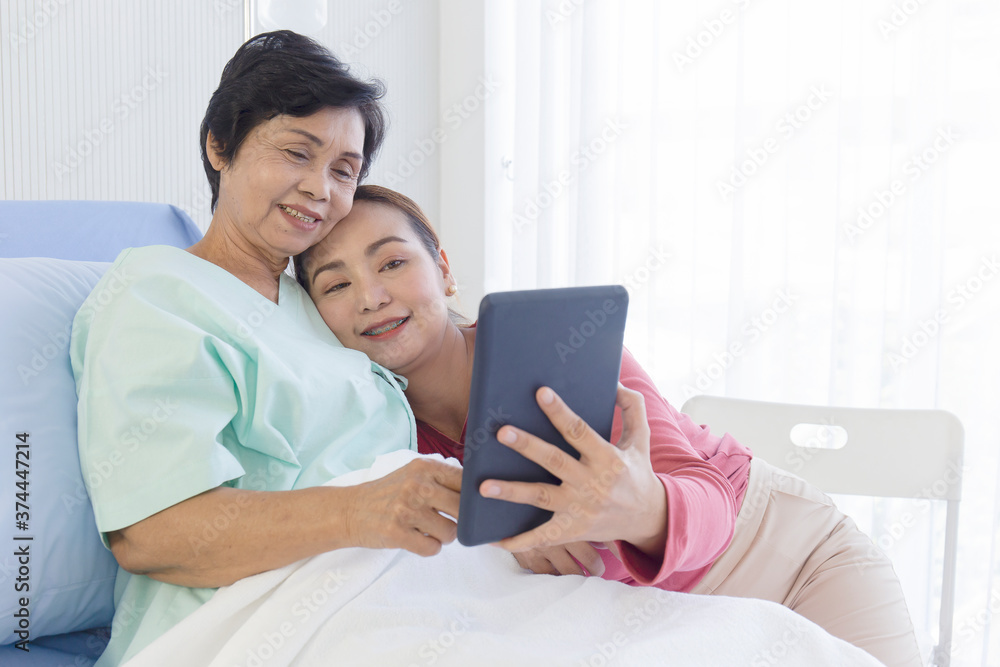 The sick mother lay on the bed in the hospital and her daughter beside each other was making video calls in a happy manner. The sick mother lay on the bed in the hospital and her daughter beside each other was making video calls in a happy manner.