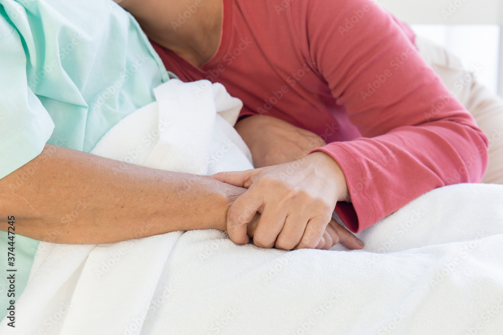 Hand in hand with a sick elderly mother lying in a hospital bed with warmth and care Hand in hand with a sick elderly mother lying in a hospital bed with warmth and care