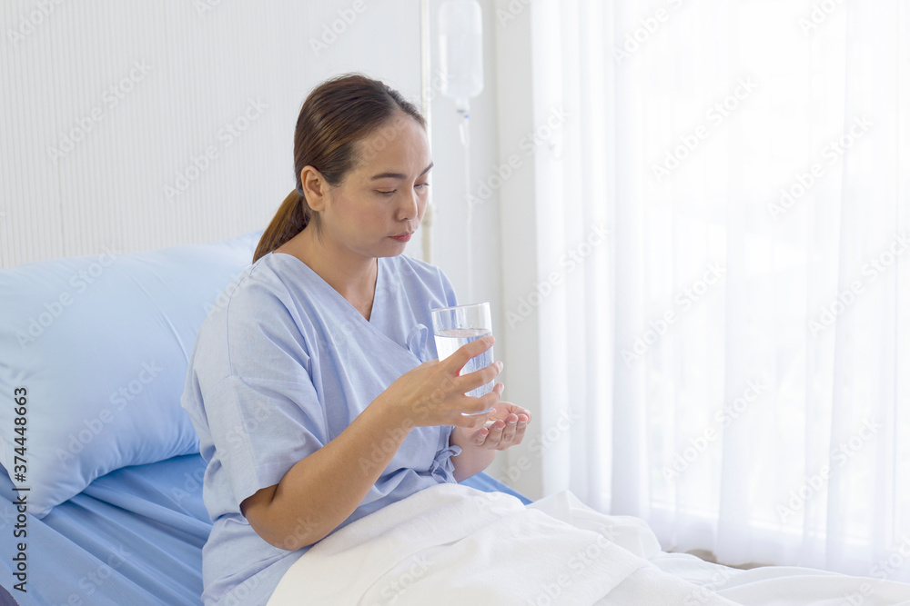 Asian female patients sitting on a bed eating medicine in the hospital Asian female patients sitting on a bed eating medicine in the hospital
