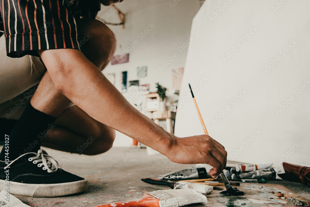 Fototapeta premium unrecognisable male artist mixing colors on palette in workshop