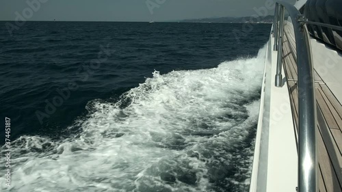 View from the deck of the yacht at the bow, close up. Side view with green sea and waves. Concept, lifestyle and freedom. Slow motion.