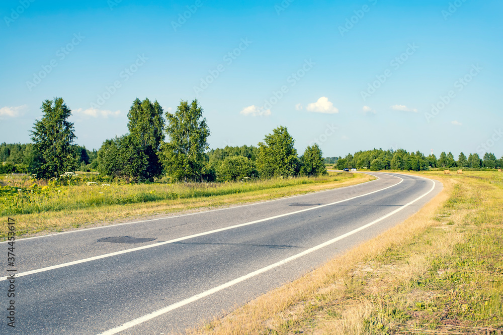 Fototapeta premium Asphalt road leading into the distance around the bend.