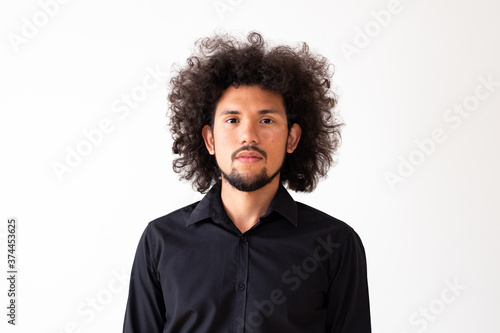 Latin American model in black shirt with big curly hair and beard, neutral background 