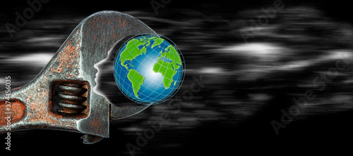 An adjustable wrench with a globe clamped in it. Human silhouette as a symbol of the impact on the ecology of the earth. Space. Protecting the ecology of the planet. Concept for design. Copspace photo