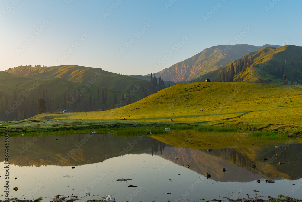 lush green landscape with small lake and mountains - mountain reflection on the water - siri paye Medows clear sky in early morning