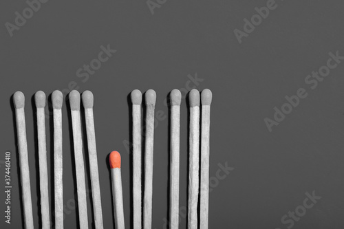 Flat lay pattern of matches with black heads and one small one with orange heads  copy space  business idea concept
