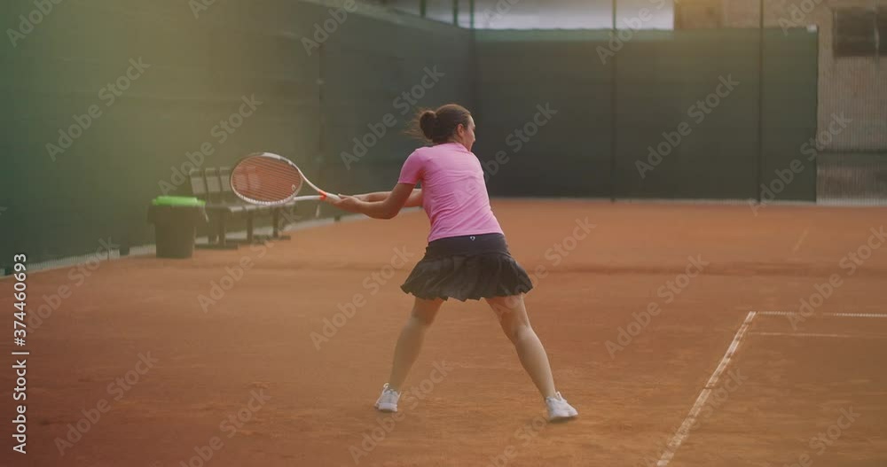 Professional equipped female beating hard the tennis ball with tennis racquet. Female tennis player in action during game. She is wearing unbranded sport clothes. Professional equipped female beating hard the tennis ball with tennis racquet. Female tennis player in action during game. She is wearing unbranded sport clothes.