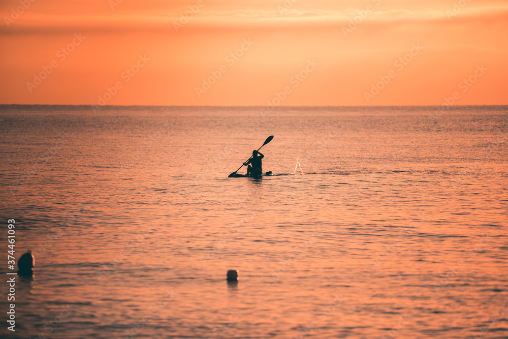 Silhouette di persone che fanno Stand up Paddle o sup, un sport che si svolge su una tavola da surf alzati all'alba sul Mare.