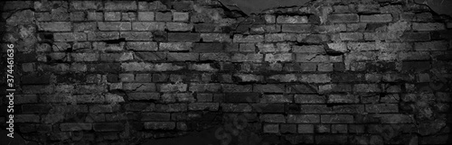 Black grunge background. Black old brick wall. Dark gray stone wall. Collapsing brickwork. Weathered stone wall.