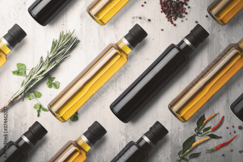 Bottles of virgin olive oil and balsamic vinegar aligned on a white wooden background with peppers, chilli and herbs photo