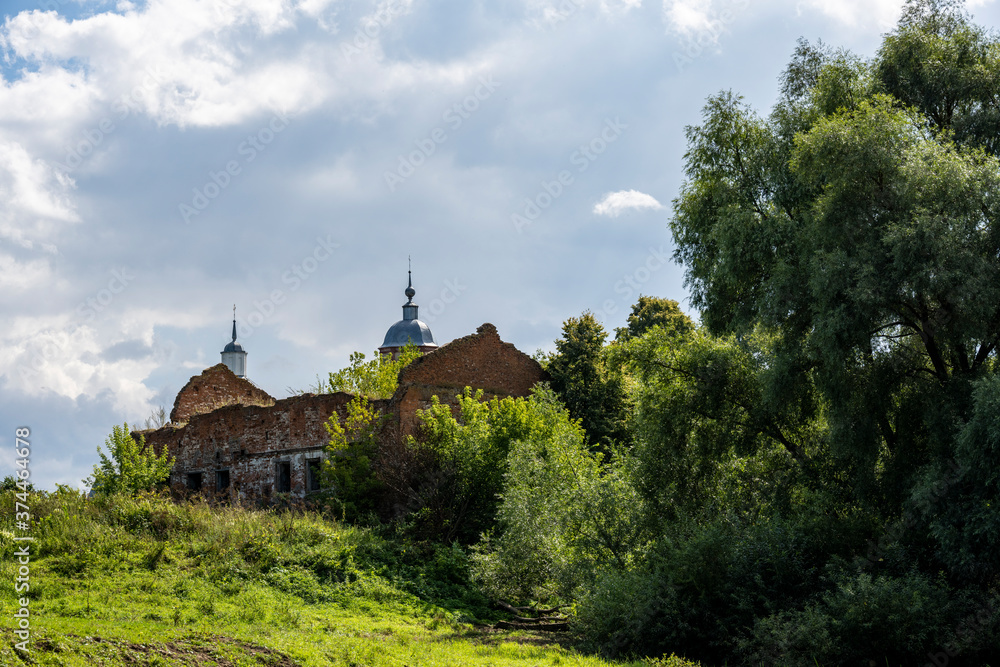 ruins of an old manor house among green trees against a blue sky ruins of an old manor house among green trees against a blue sky