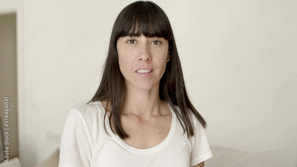 Happy dark haired young woman posing in home interior, looking at camera, smiling, tilting head. Closeup shot, front view. Woman at home or housewife concept Happy dark haired young woman posing in home interior, looking at camera, smiling, tilting head. Closeup shot, front view. Woman at home or housewife concept