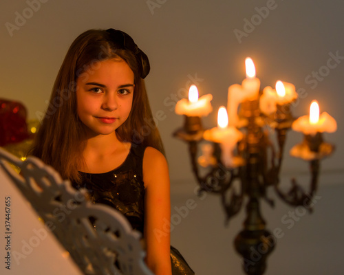 Beautiful Girl Playing Piano Decorated with Candles in Candlesticks