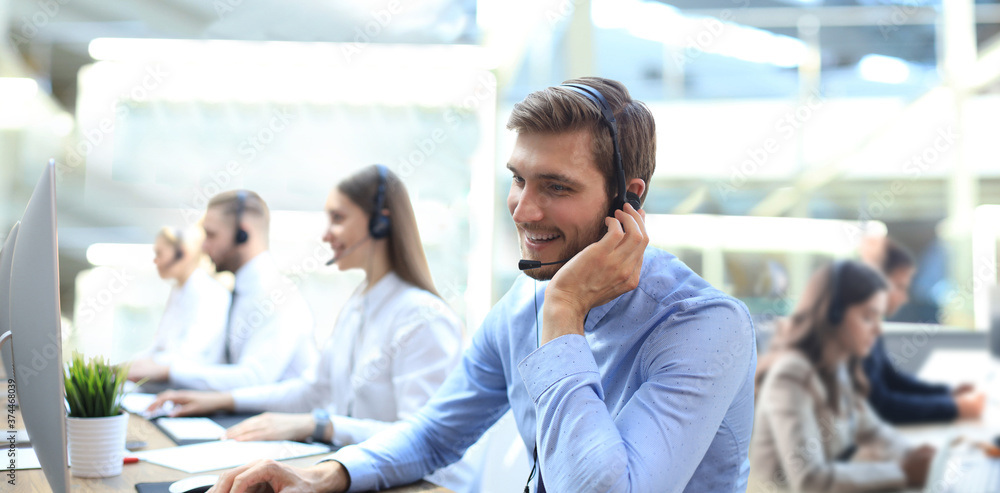 © ty - Portrait of call center worker accompanied by his team. Smiling customer support operator at work.