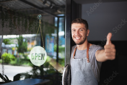 Young Chef owner of sushi restaurant smiling while turning the sign for the reopening of his place after the quarantine due to covid-19. .Small  business open, Thailand, Koh Phangan