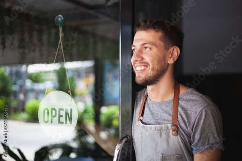 Young Chef owner of sushi restaurant smiling while turning the sign for the reopening of his place after the quarantine due to covid-19. .Small  business open, Thailand, Koh Phangan