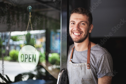 Young Chef owner of sushi restaurant smiling while turning the sign for the reopening of his place after the quarantine due to covid-19. .Small  business open, Thailand, Koh Phangan