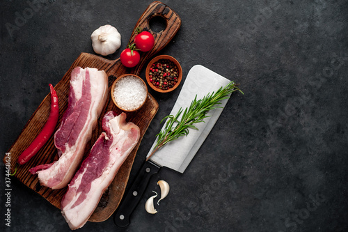 raw pork breast with spices on a cutting board on a stone background with copy space for your text